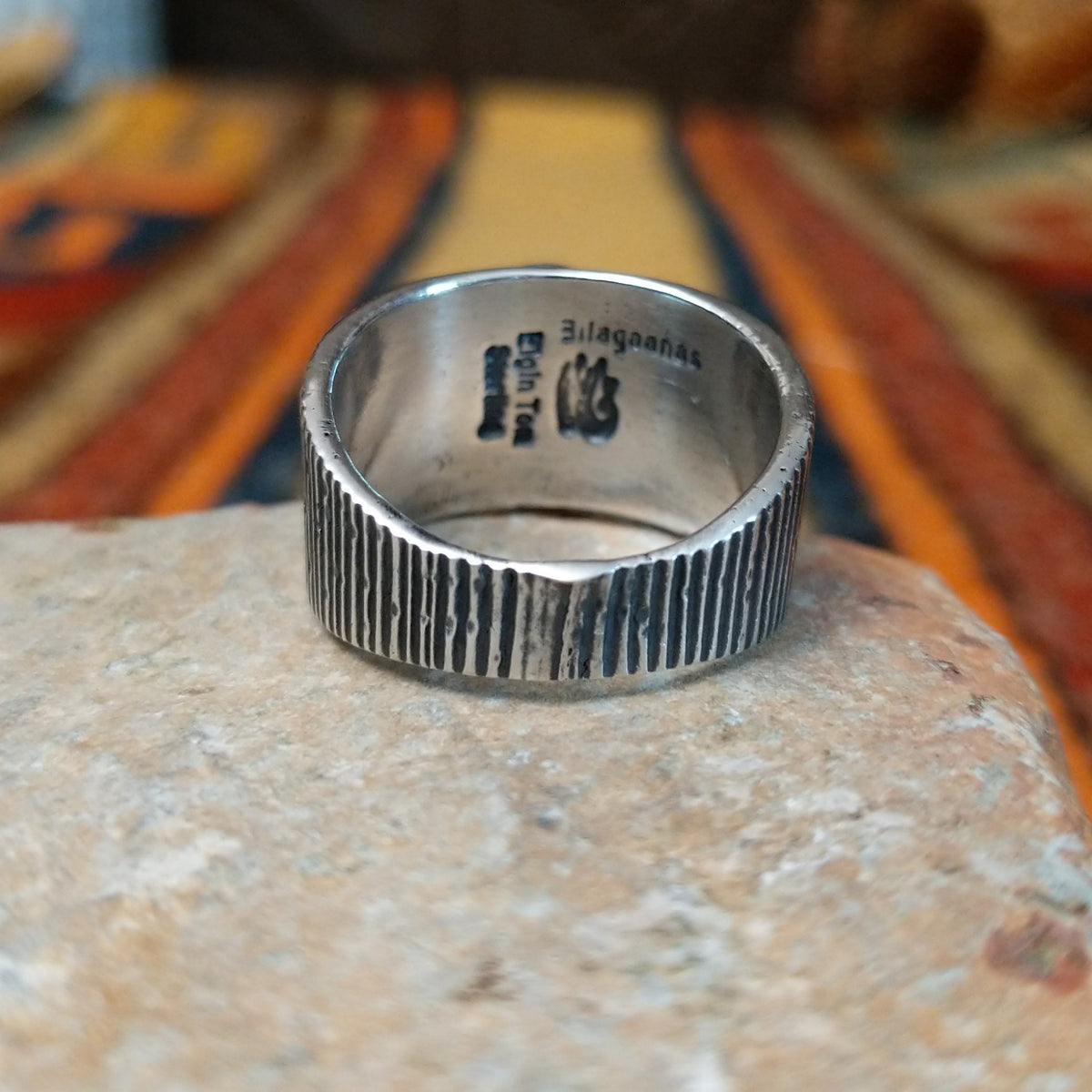 Sonoran Gold Turquoise Ring by Elgin Tom featuring a round blue and green turquoise stone with natural matrix, set in a wide sterling silver band with textured vertical lines; underside view.