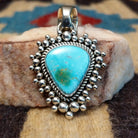 Sterling silver pendant featuring Sonoran Gold turquoise with green-blue tones and natural matrix, accented by dotted silver beadwork and handcrafted by Navajo artist Artie Yellowhorse.  Front view.