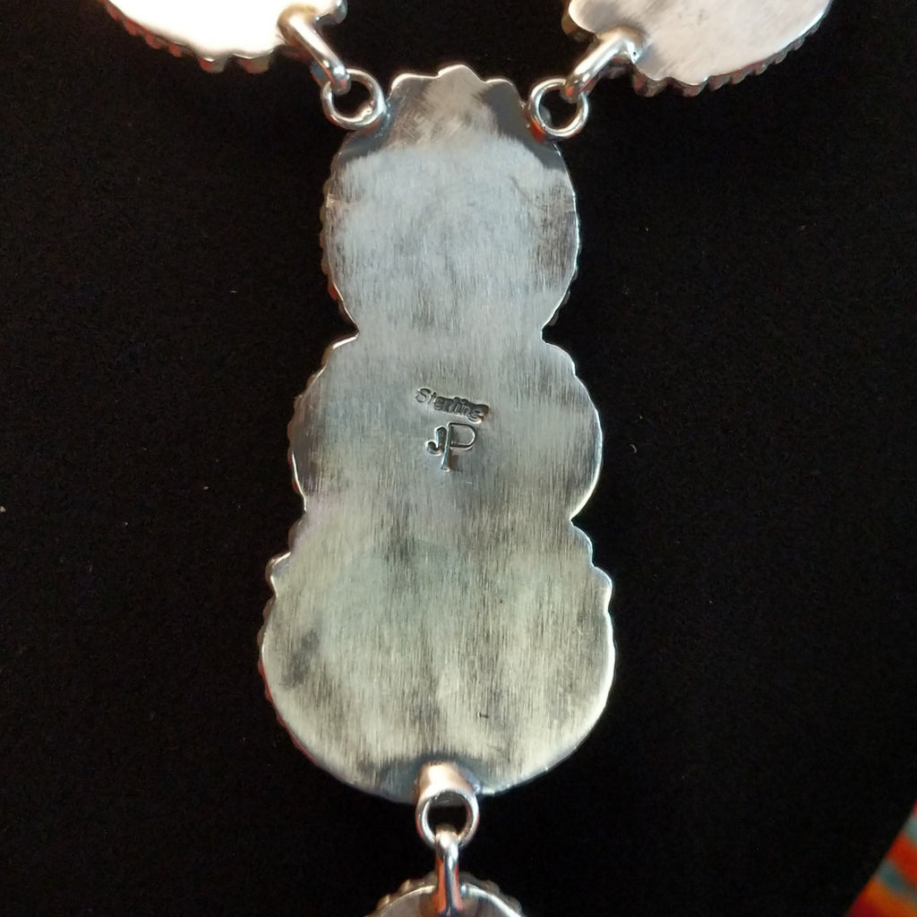 The artisan's initials are stamped onto the back of the necklace bezel.