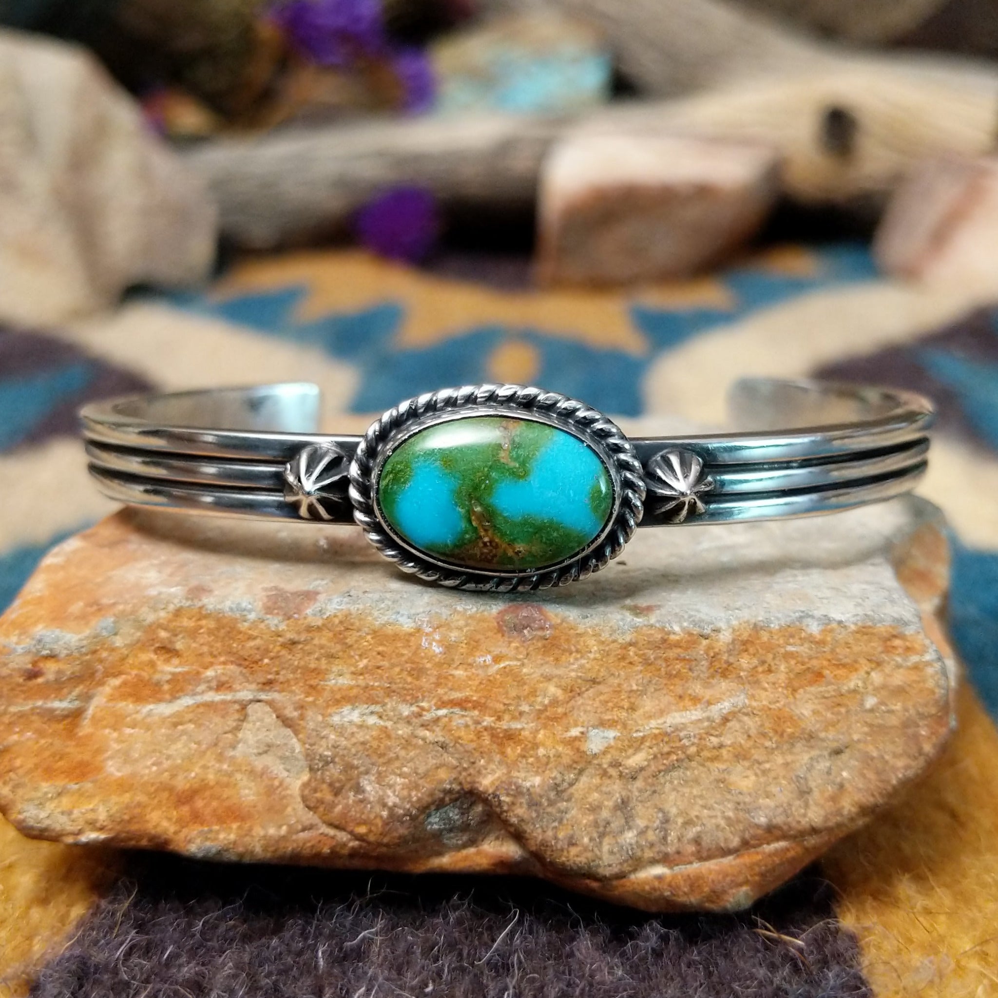 Handcrafted sterling silver cuff by Raymond Coriz featuring an oval Sonoran Gold turquoise cabochon in a twisted rope bezel on a three-wire cuff with hand-stamped fan accents.