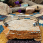 Handcrafted sterling silver cuff by Raymond Coriz featuring an oval Sonoran Gold turquoise cabochon in a twisted rope bezel on a three-wire cuff with hand-stamped fan accents; underside view.