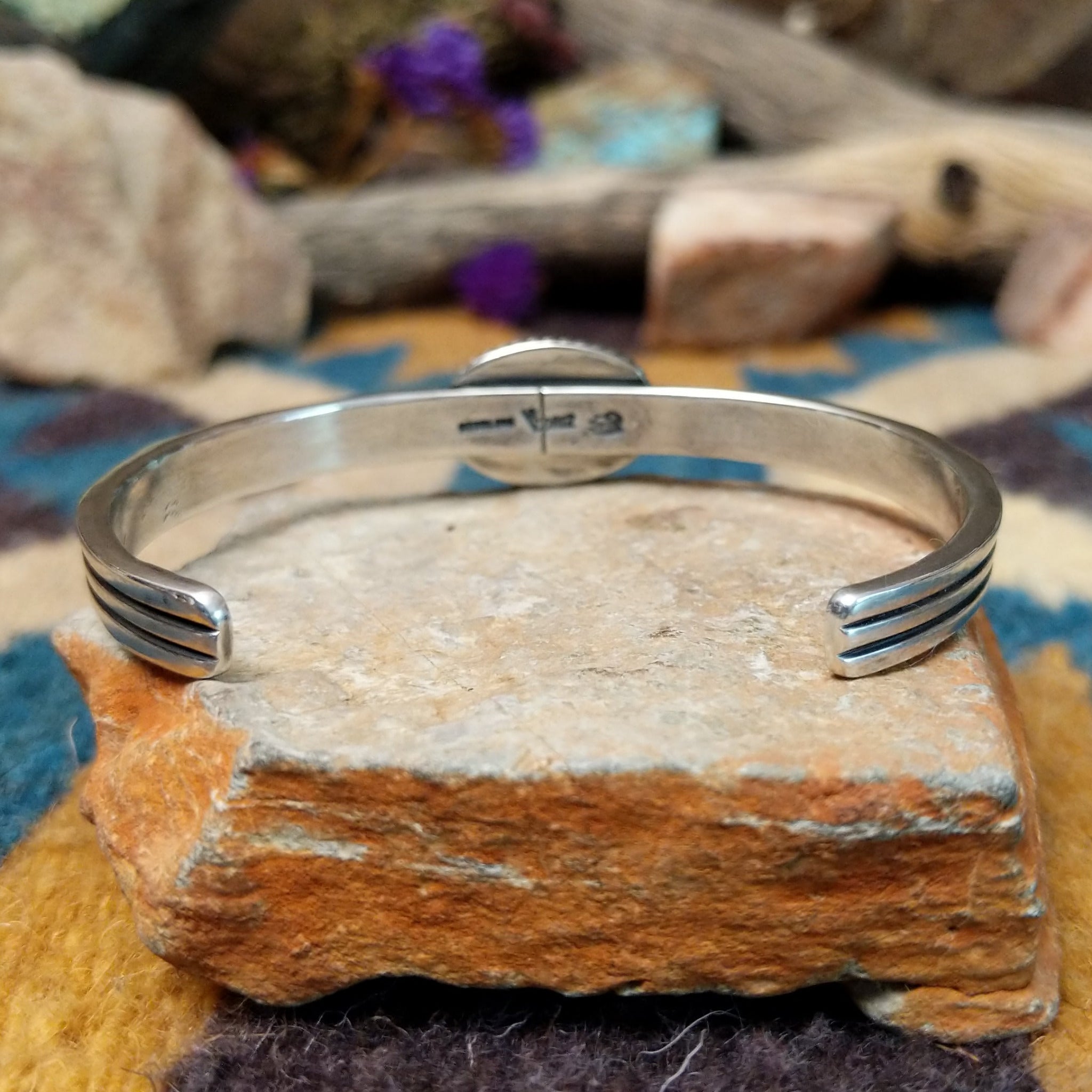 Handcrafted sterling silver cuff by Raymond Coriz featuring an oval Sonoran Gold turquoise cabochon in a twisted rope bezel on a three-wire cuff with hand-stamped fan accents; underside view.