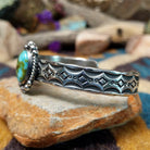 Handcrafted Navajo sterling silver cuff by Michael Thompson featuring an oval Sonoran Gold turquoise cabochon with a rope bezel, silver bead accents, and a hand-stamped geometric cuff band; side view.