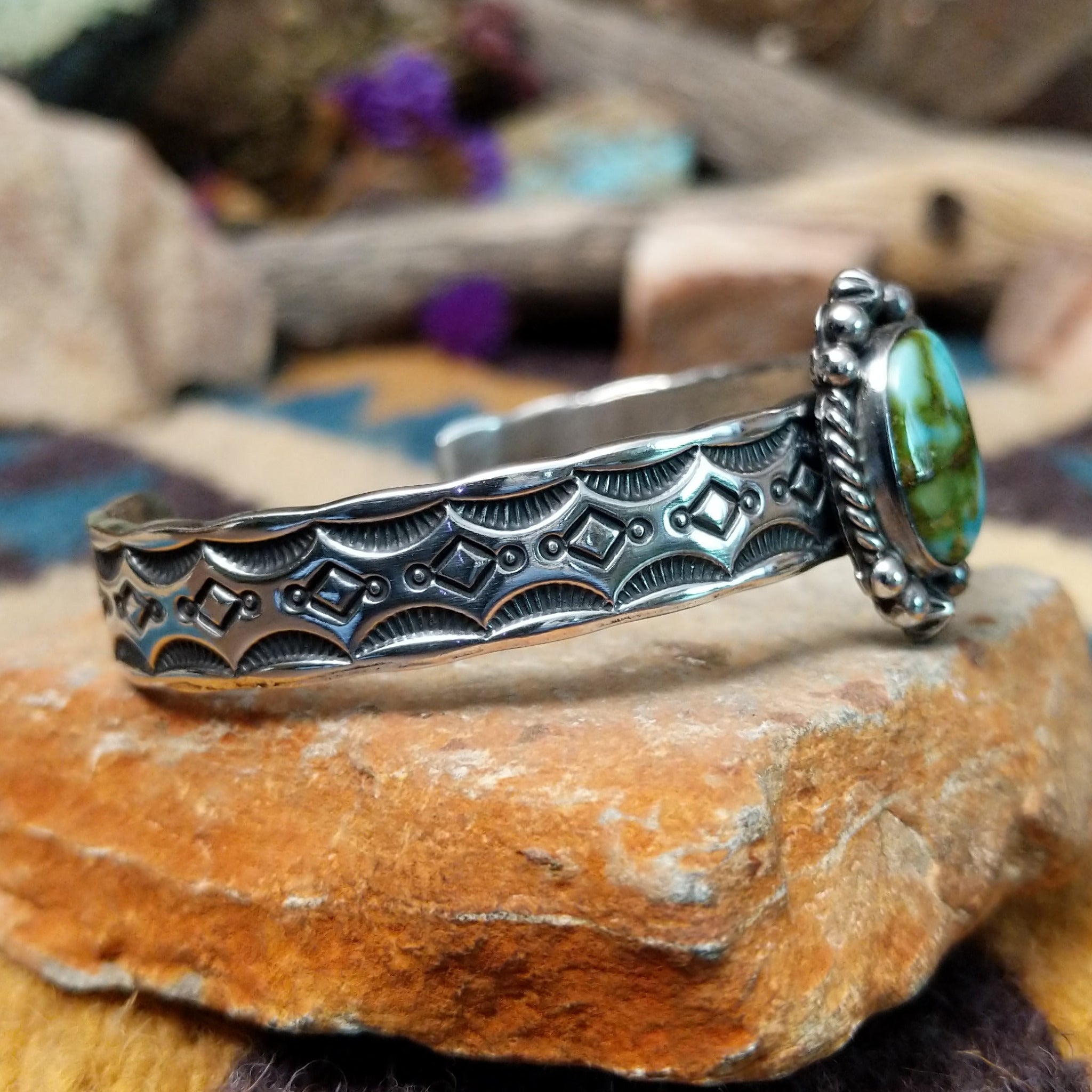 Handcrafted Navajo sterling silver cuff by Michael Thompson featuring an oval Sonoran Gold turquoise cabochon with a rope bezel, silver bead accents, and a hand-stamped geometric cuff band; side view.