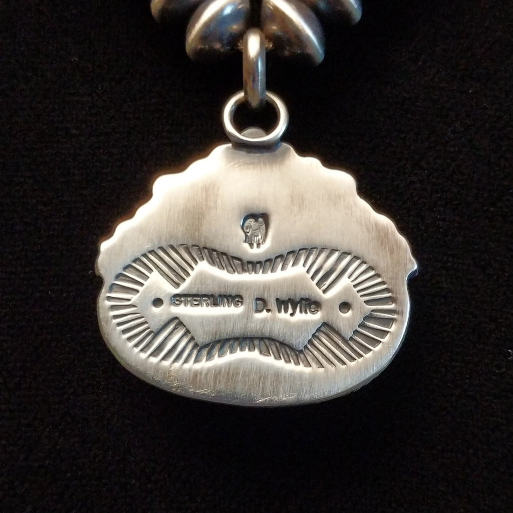 The back side of the pendant features the artisan's signature.