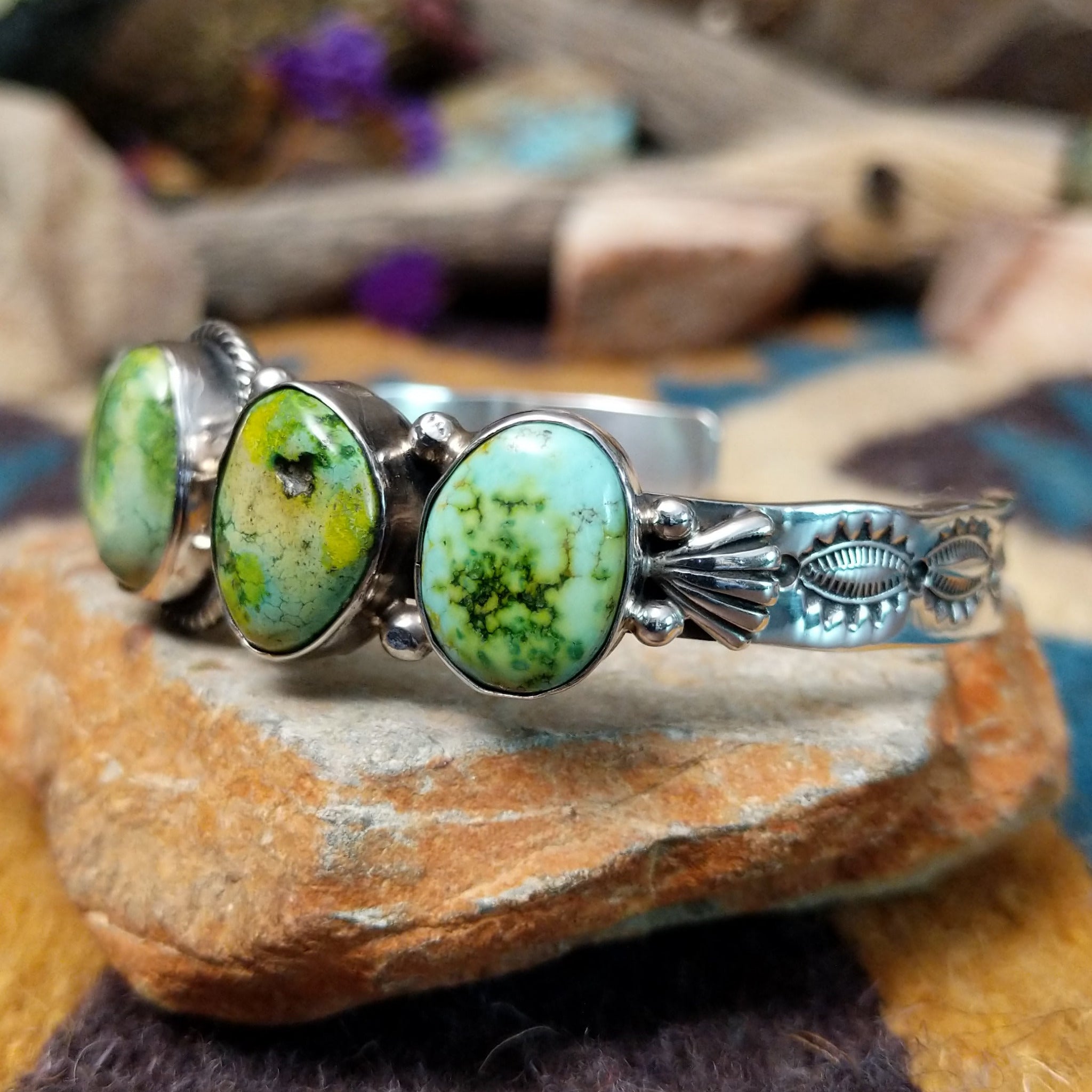 Handcrafted Navajo sterling silver cuff by Roie Jaque featuring five Sonoran Gold turquoise cabochons, including a rope-bordered center stone accented with polished silver bead details; side view.