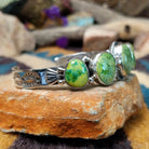 Handcrafted Navajo sterling silver cuff by Roie Jaque featuring five Sonoran Gold turquoise cabochons, including a rope-bordered center stone accented with polished silver bead details; side view.