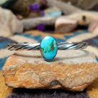 Handcrafted sterling silver twisted cuff by Raymond Coriz featuring an oval Sonoran Gold turquoise cabochon with vibrant blue, green, and natural golden matrix.