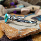 Handcrafted sterling silver twisted cuff by Raymond Coriz featuring an oval Sonoran Gold turquoise cabochon with vibrant blue, green, and natural golden matrix; side view.