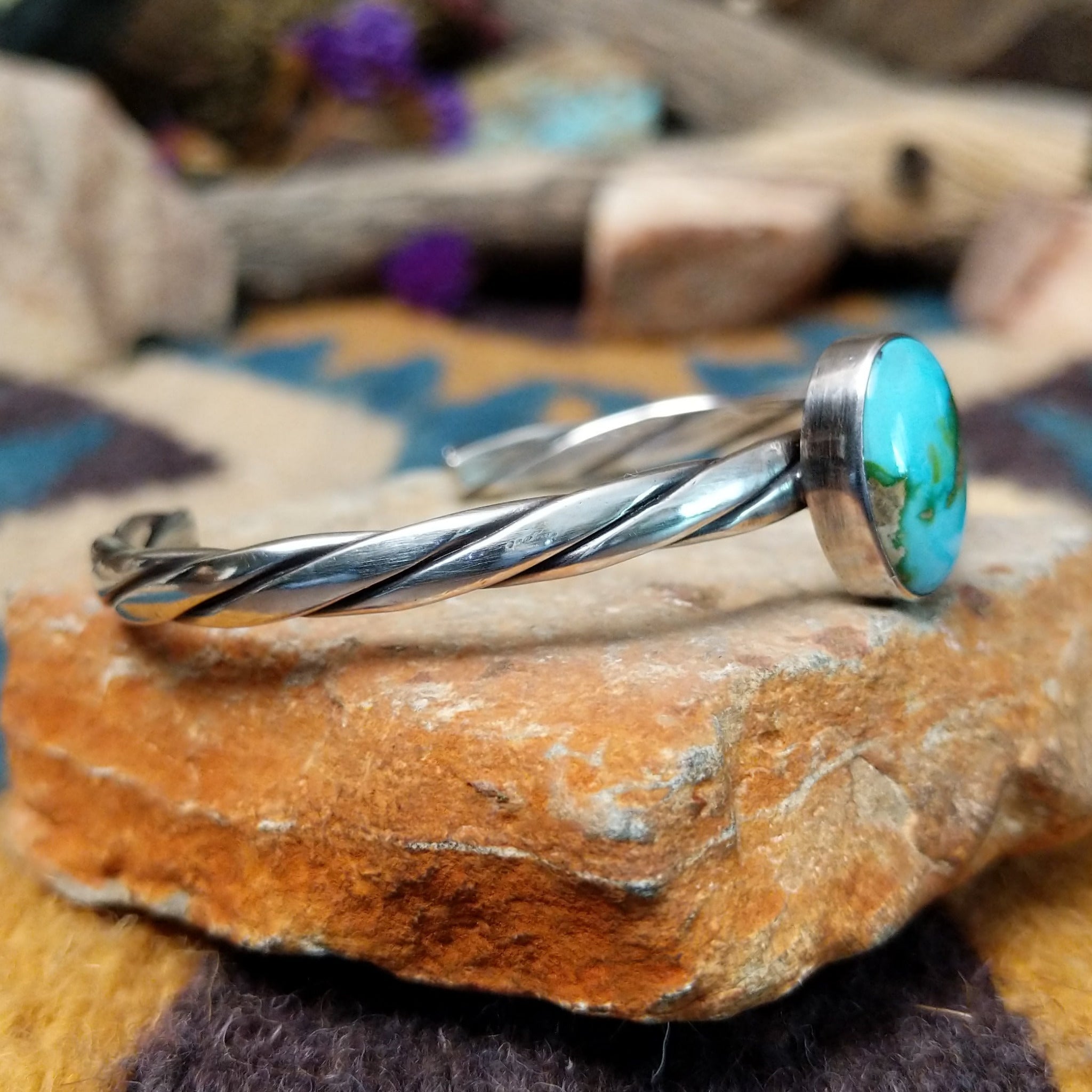 Handcrafted sterling silver twisted cuff by Raymond Coriz featuring an oval Sonoran Gold turquoise cabochon with vibrant blue, green, and natural golden matrix; side view.