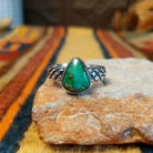 Sonoran Gold Turquoise Ring by Raymond Coriz featuring a pear-shaped green turquoise stone with natural matrix, set in sterling silver with a smooth bezel and decorative braided band.