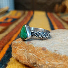 Sonoran Gold Turquoise Ring by Raymond Coriz featuring a pear-shaped green turquoise stone with natural matrix, set in sterling silver with a smooth bezel and decorative braided band; side view.
