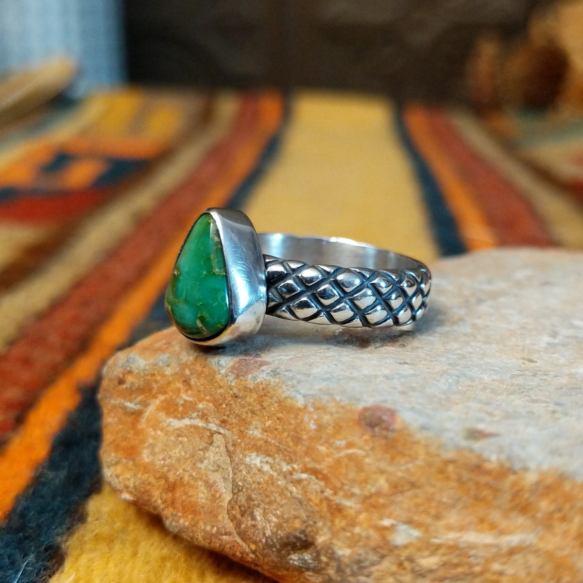 Sonoran Gold Turquoise Ring by Raymond Coriz featuring a pear-shaped green turquoise stone with natural matrix, set in sterling silver with a smooth bezel and decorative braided band; side view.