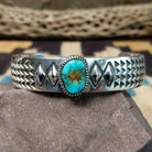 Sonoran Mountain turquoise cuff by Rydel Victor Curtis, featuring an oval blue Sonoran Mountain turquoise stone with natural golden-brown matrix set in a handcrafted sterling silver cuff with intricate geometric stampwork.