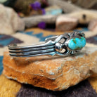 Handcrafted Navajo sterling silver cuff by Raymond Coriz featuring an oval Sonoran Mountain turquoise cabochon with polished silver bead accents, openwork scroll detailing, and a triple-split cuff design;  side view.