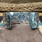 Spiderweb #8 turquoise cuff by Andrew Gordon, featuring an oval blue Spiderweb #8 turquoise stone with natural spiderweb matrix set in a handcrafted sterling silver cuff with hand-stamped fan and geometric designs; underside view.
