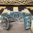 Spiderweb #8 turquoise cuff by Andrew Gordon, featuring an oval blue Spiderweb #8 turquoise stone with natural spiderweb matrix set in a handcrafted sterling silver cuff with hand-stamped fan and geometric designs; underside detail view.