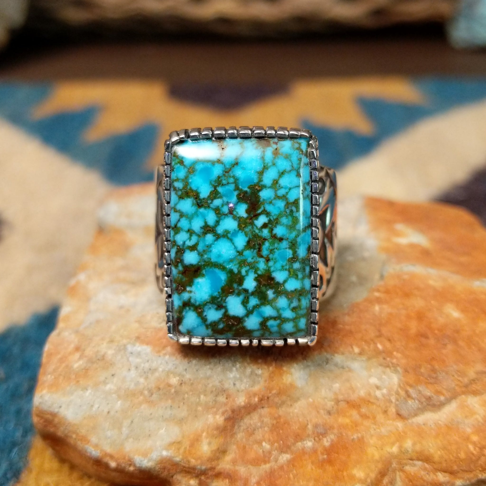 Spiderweb Kingman Turquoise Ring by Joe Piaso Jr. featuring a large rectangular sky-blue Kingman turquoise stone with an intricate dark spiderweb matrix, set in a sterling silver serrated bezel with an openwork silver band, displayed on a natural stone.