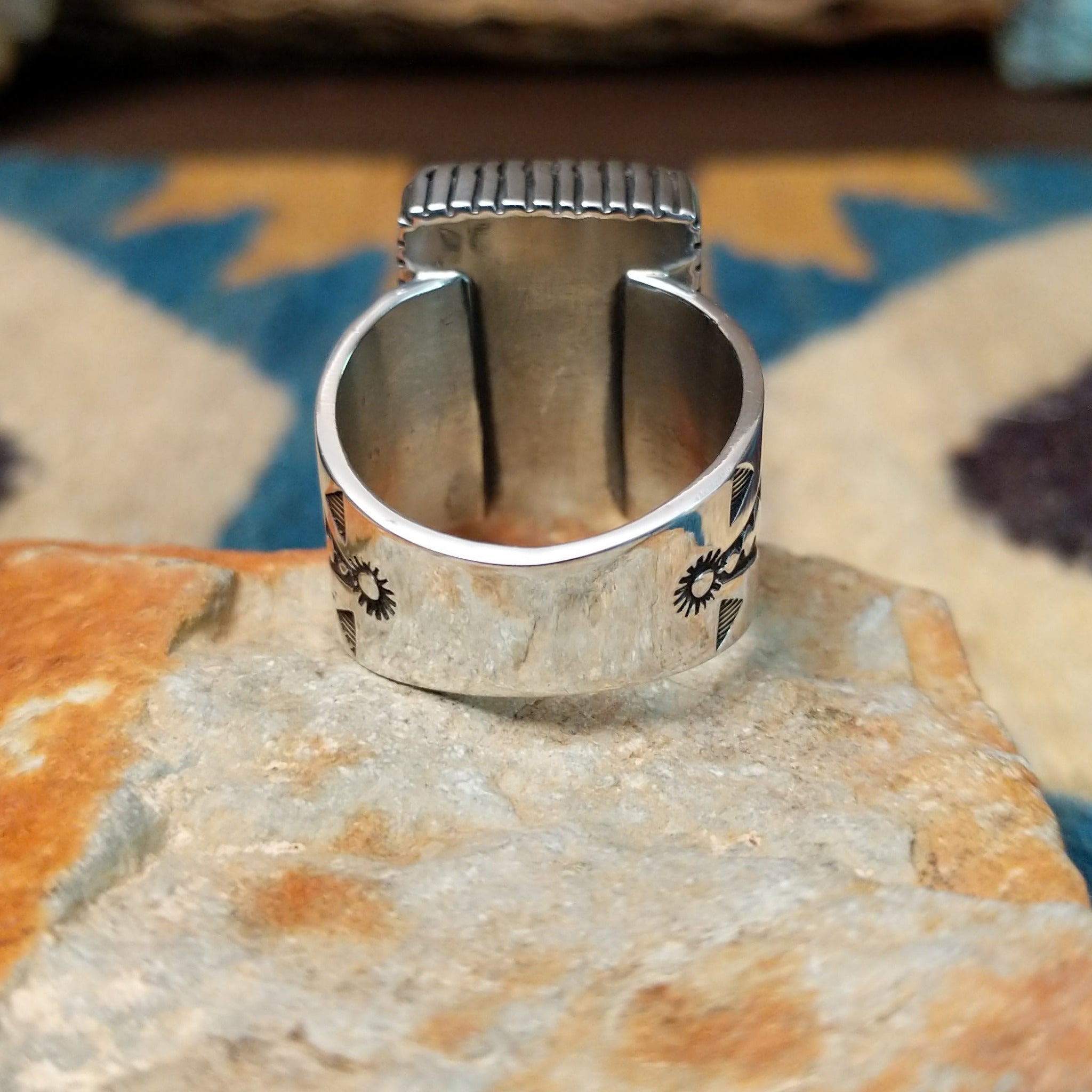 Spiderweb Kingman Turquoise Ring by Joe Piaso Jr. featuring a large rectangular sky-blue Kingman turquoise stone with an intricate dark spiderweb matrix, set in a sterling silver serrated bezel with an openwork silver band, displayed on a natural stone; underside view.
