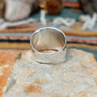 Handcrafted sterling silver ring by Raymond Coriz featuring an intricate rectangular spiral design with stamped details, an oxidized background, and a wide polished silver band; underside view.