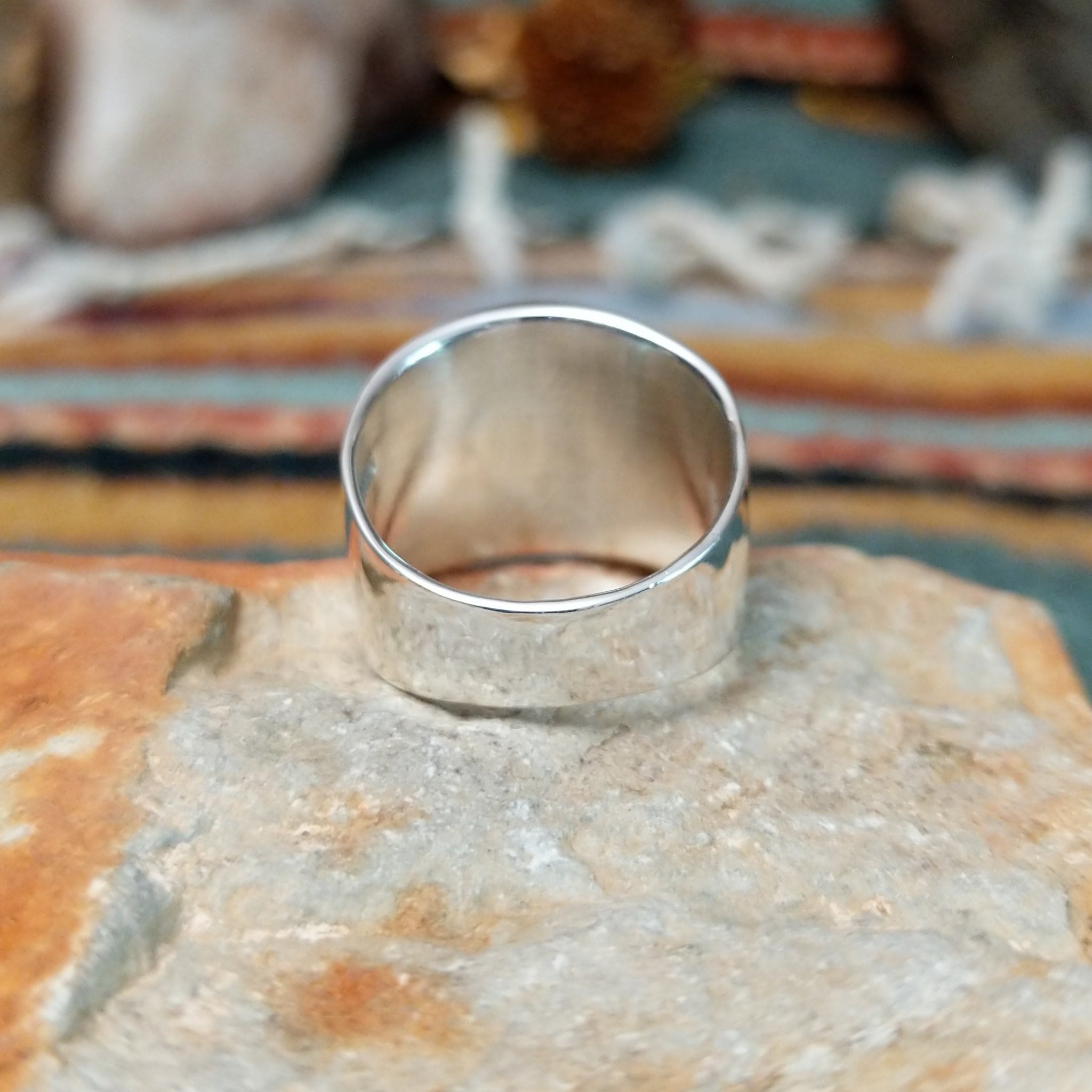 Handcrafted sterling silver ring by Raymond Coriz featuring an intricate rectangular spiral design with stamped details, an oxidized background, and a wide polished silver band; underside view.