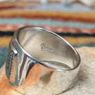 Handcrafted sterling silver ring by Raymond Coriz featuring an intricate rectangular spiral design with stamped details, an oxidized background, and a wide polished silver band; artisan stamp.