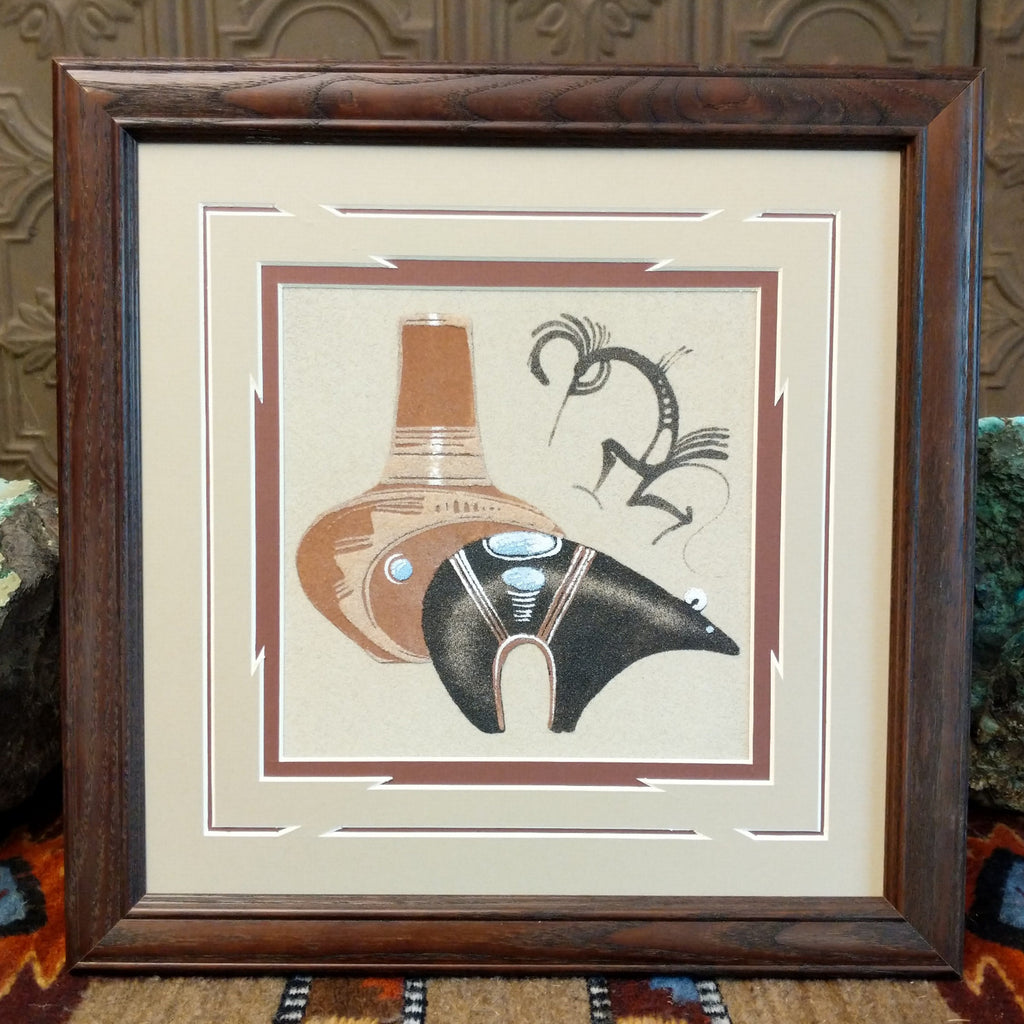 Sand used to depict a black spirit bear and terracotta pot set within a wooden frame.