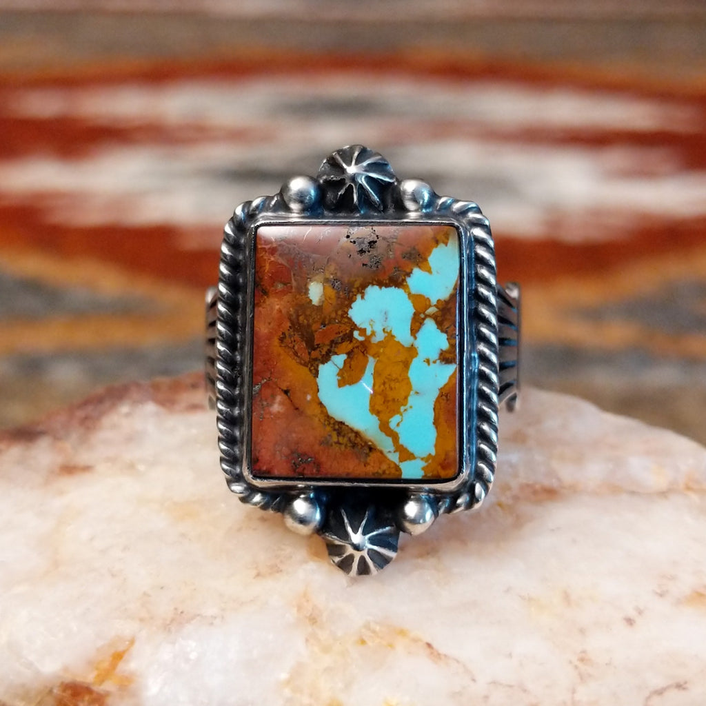 Square boulder turquoise set within sterling silver bezel with twisted rope and dotted accents making the centerpiece of the sterling silver ring.