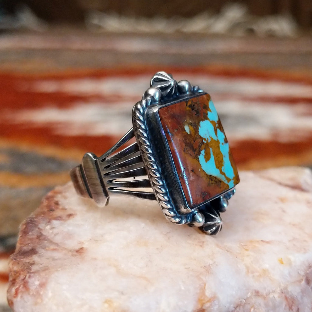 Square boulder turquoise set within sterling silver bezel with twisted rope and dotted accents making the centerpiece of the sterling silver ring.