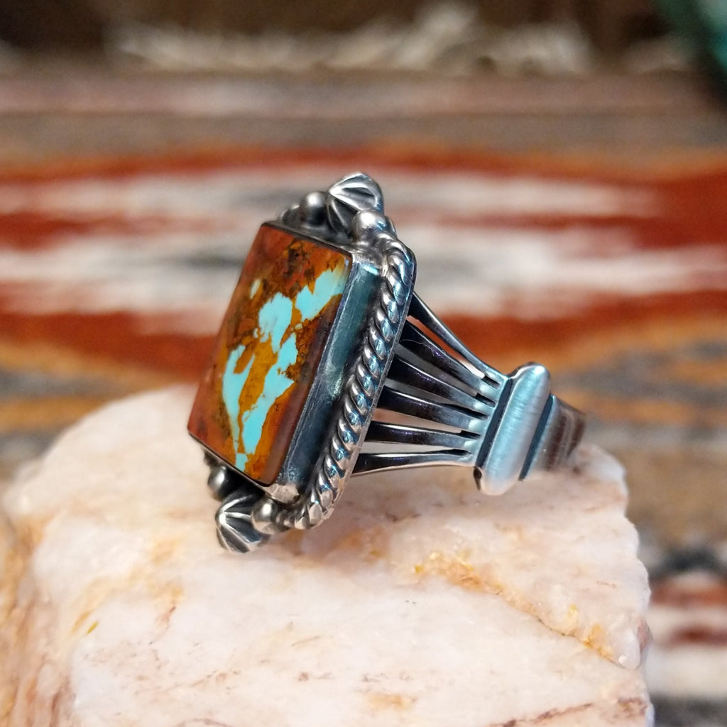Square boulder turquoise set within sterling silver bezel with twisted rope and dotted accents making the centerpiece of the sterling silver ring.