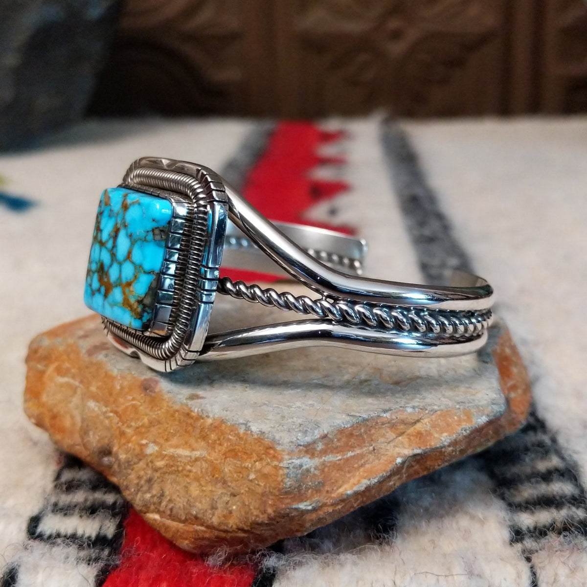 Silver cuff by Walter Vandever featuring a large square Kingman turquoise stone with brown matrix, framed by detailed silverwork and a split-band design with a twisted center strand; side view.