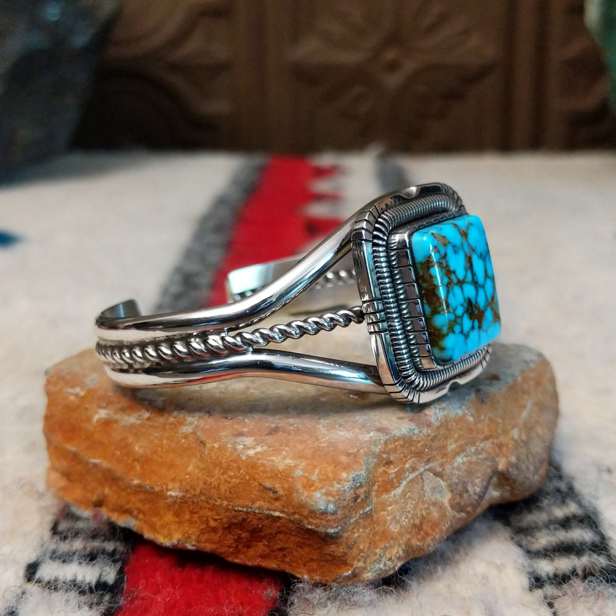 Silver cuff by Walter Vandever featuring a large square Kingman turquoise stone with brown matrix, framed by detailed silverwork and a split-band design with a twisted center strand; side view.