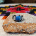 This Square Lapis Ring by Raymond Coriz features a square blue lapis stone set in sterling silver with a twisted rope border, silver bead accents, and a multi-band design.