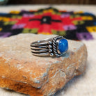 This Square Lapis Ring by Raymond Coriz features a square blue lapis stone set in sterling silver with a twisted rope border, silver bead accents, and a multi-band design; side view.
