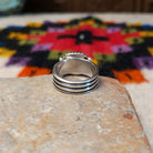 This Square Lapis Ring by Raymond Coriz features a square blue lapis stone set in sterling silver with a twisted rope border, silver bead accents, and a multi-band design; underside view.