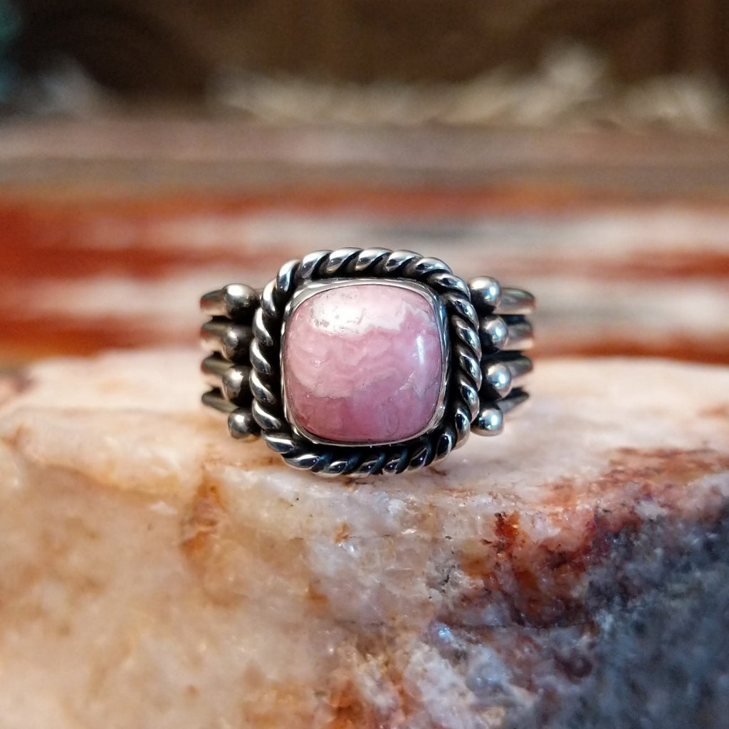 Square rhodochrosite framed by the twisted rope, with a dotted and layered band of the ring.