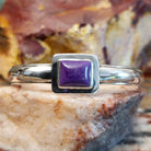 Sugilite set within the square bezel of of the polished silver cuff.
