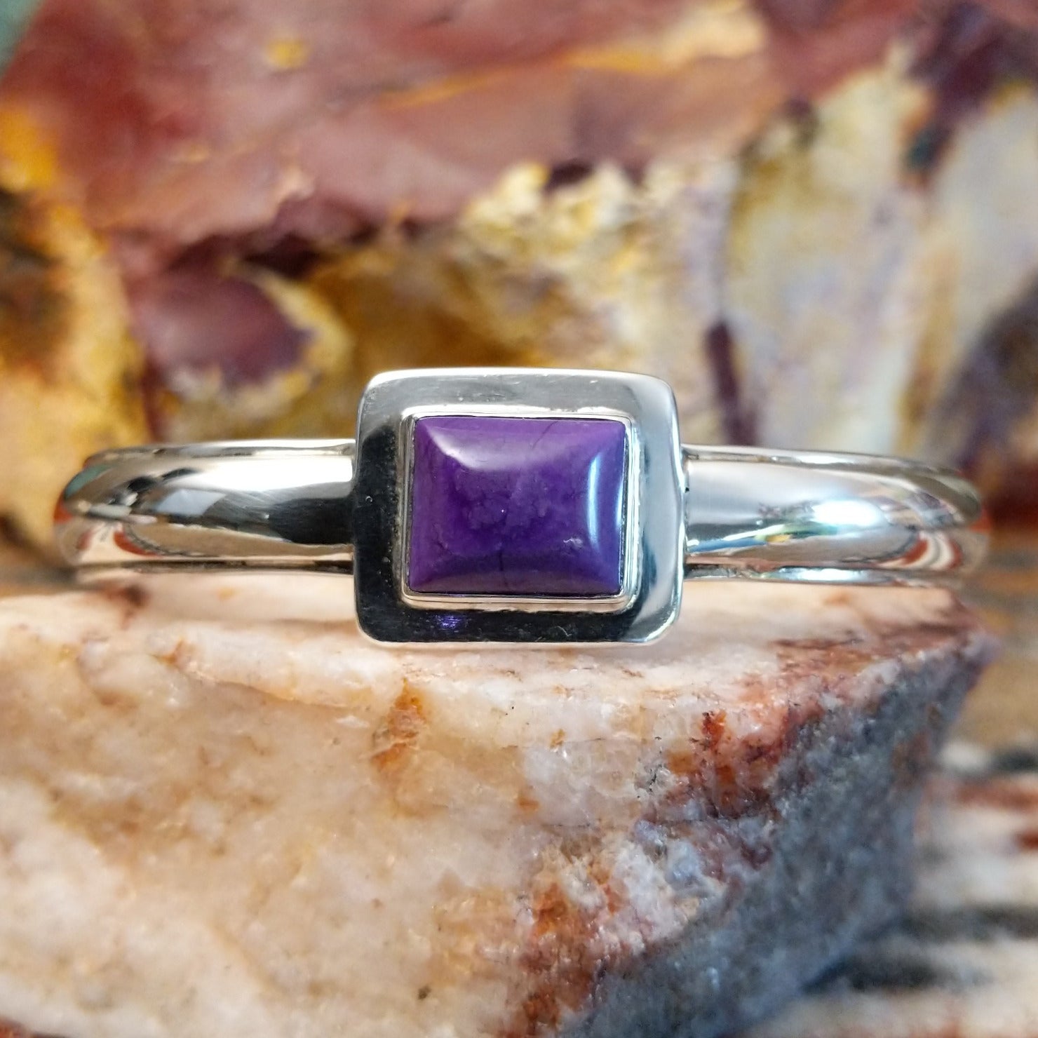 Sugilite set within the square bezel of of the polished silver cuff.
