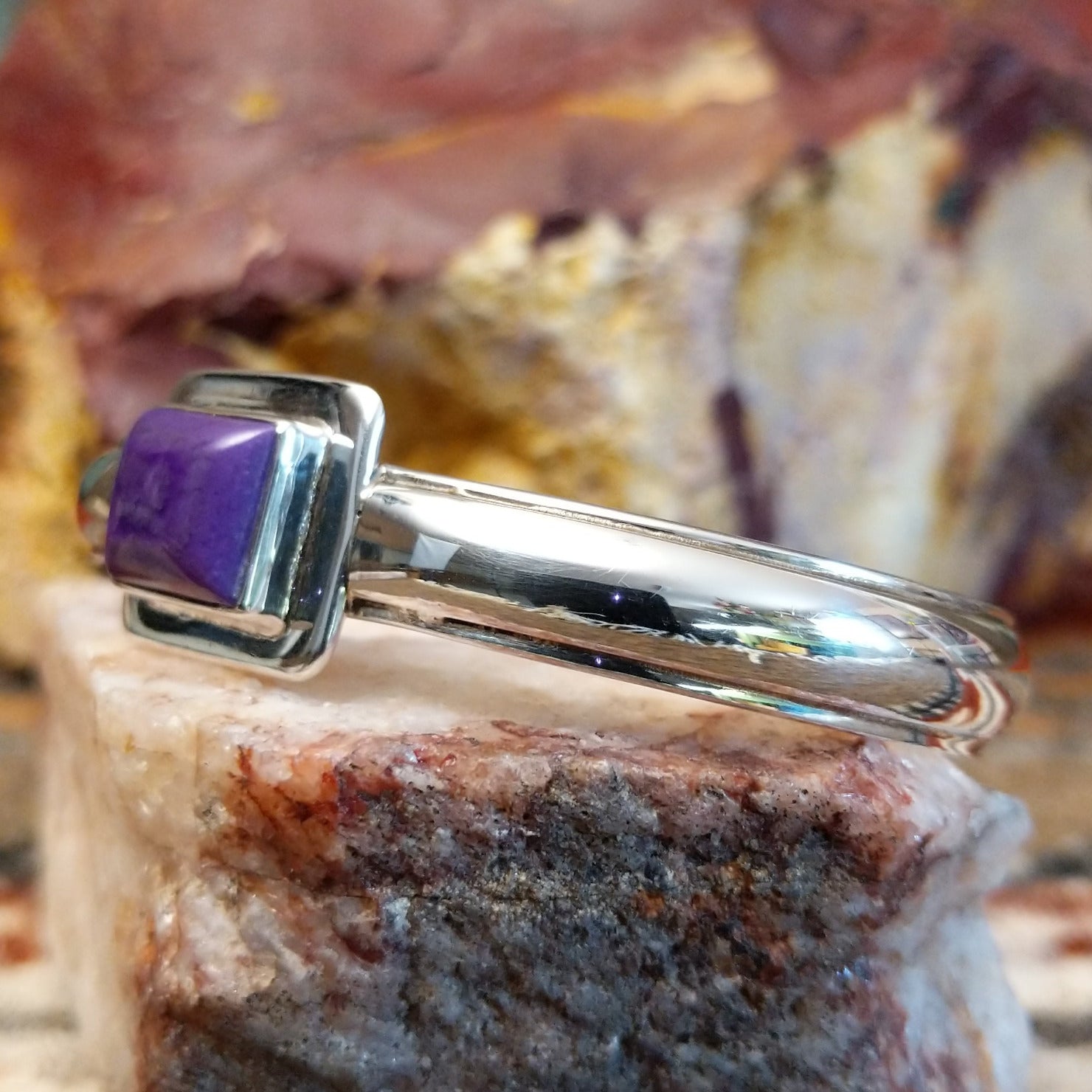 Sugilite set within the square bezel of of the polished silver cuff.