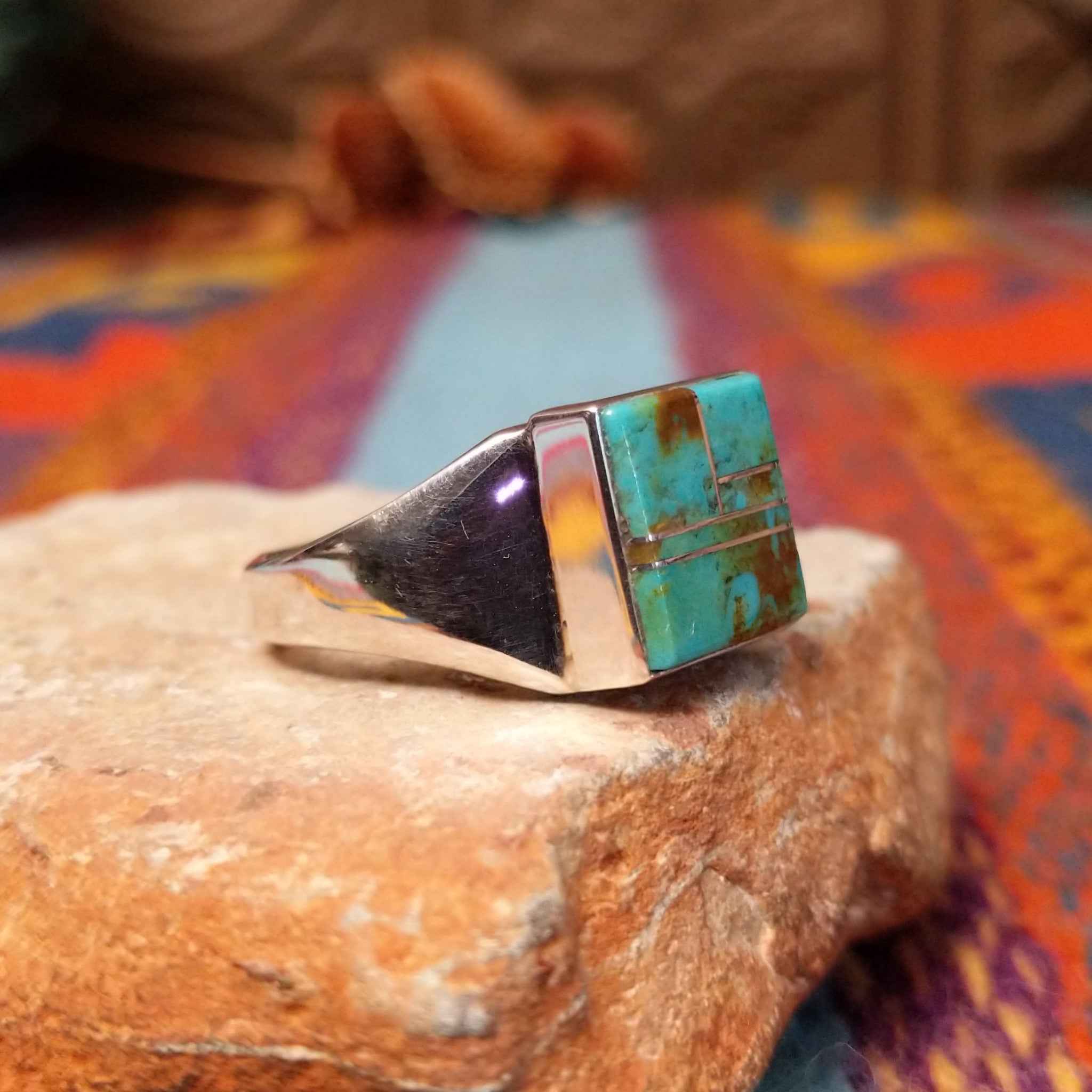 Square Turquoise Inlay Ring by Wilbert Grey featuring geometric turquoise inlay with natural brown matrix, separated by Sterling Silver channels and set on a polished silver band; side view.