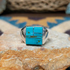Handcrafted Navajo sterling silver ring by Wilbert Grey featuring a square turquoise inlay with sterling silver channel accents in a polished geometric setting.