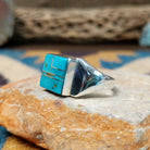 Handcrafted Navajo sterling silver ring by Wilbert Grey featuring a square turquoise inlay with sterling silver channel accents in a polished geometric setting; side view.