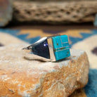 Handcrafted Navajo sterling silver ring by Wilbert Grey featuring a square turquoise inlay with sterling silver channel accents in a polished geometric setting; side view.