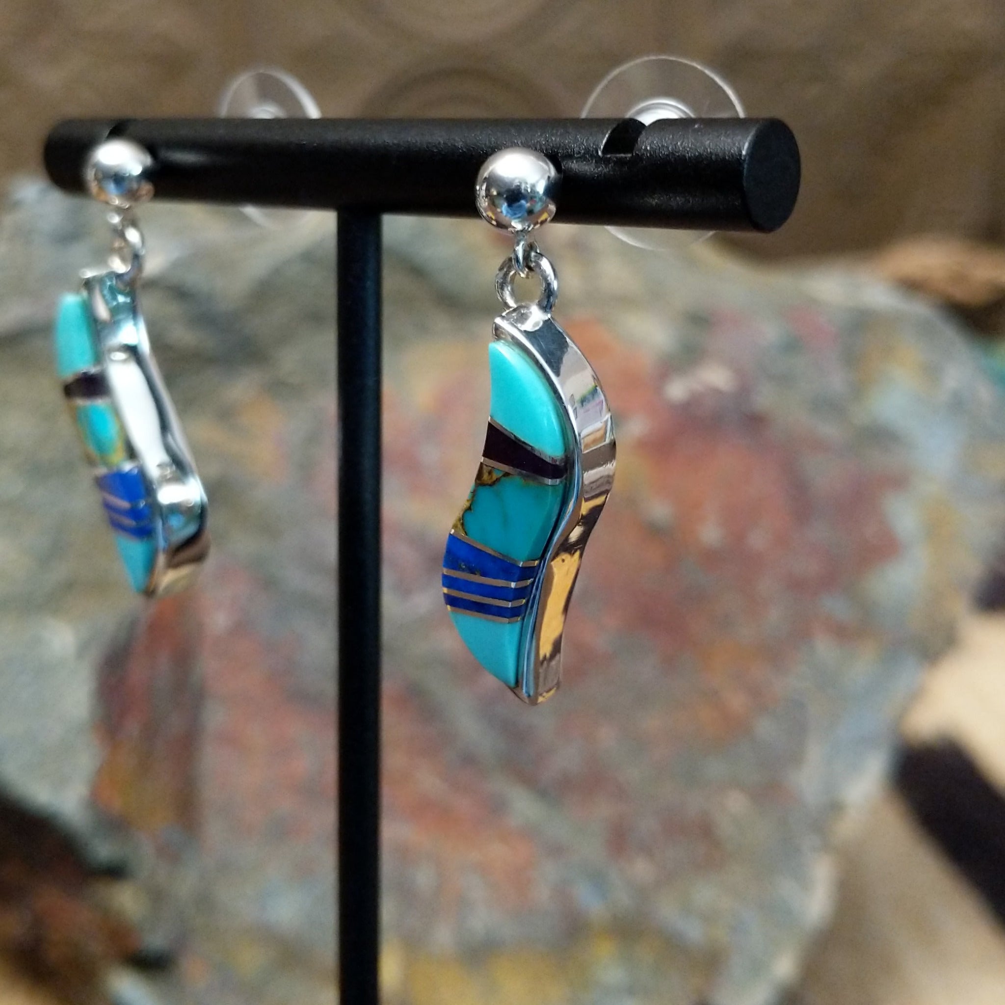 Handcrafted sterling silver inlay earrings by O. James, featuring a curved design with colorful multistone inlay; side view.