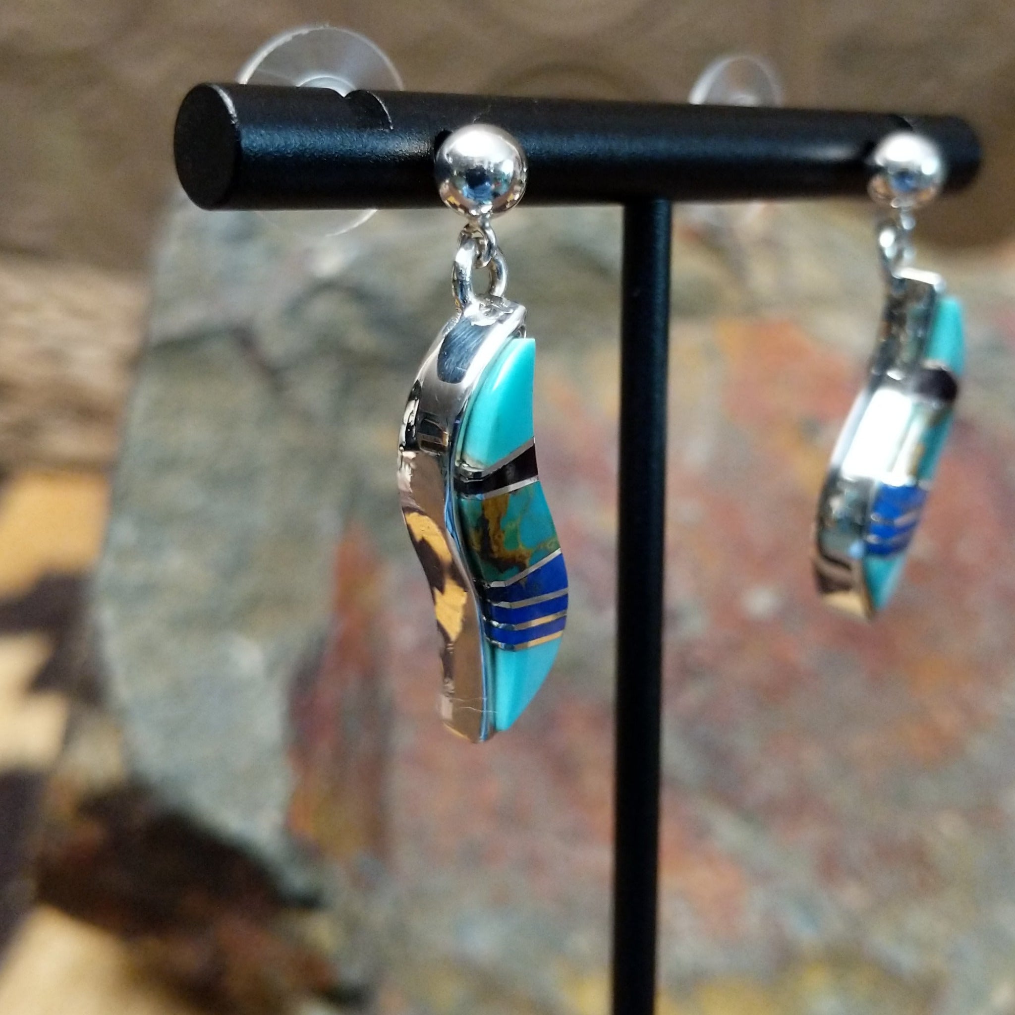 Handcrafted sterling silver inlay earrings by O. James, featuring a curved design with colorful multistone inlay; side view.
