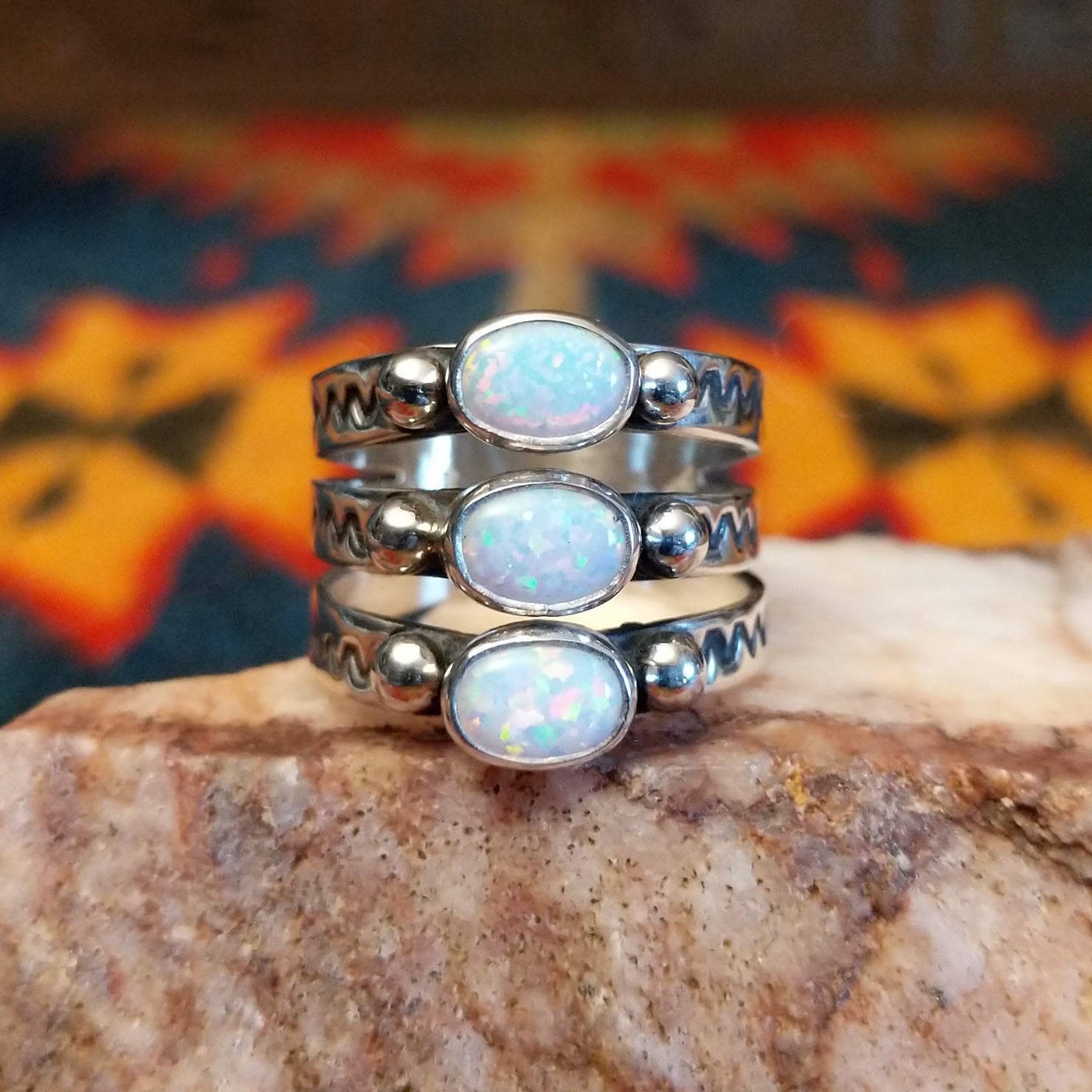 Stacked sterling silver ring with manmade opal set in oval bezels, featuring stamped patterns on the band.