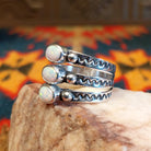 Stacked sterling silver ring with manmade opal set in oval bezels, featuring stamped patterns on the band.
