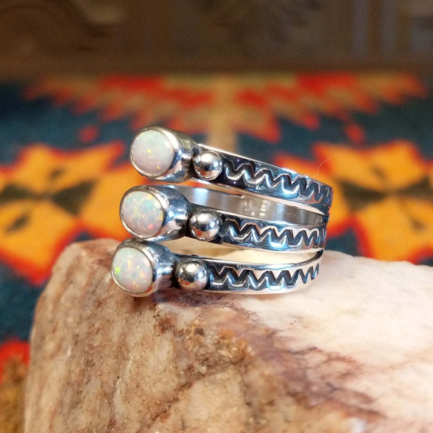 Stacked sterling silver ring with manmade opal set in oval bezels, featuring stamped patterns on the band.
