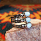 Stacked sterling silver ring with manmade opal set in oval bezels, featuring stamped patterns on the band.