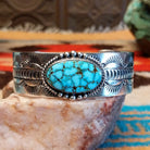 Sterling silver cuff bracelet with Kingman turquoise set in the oval bezel, framed by twisted rope, dotted accents, and stamped designs on the band.